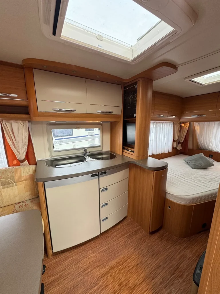 Interiér karavanu se zmodernizovaným vybavením, kuchyňkou a ložnicí. Pohodlný prostor pro dovolenou na cestách.