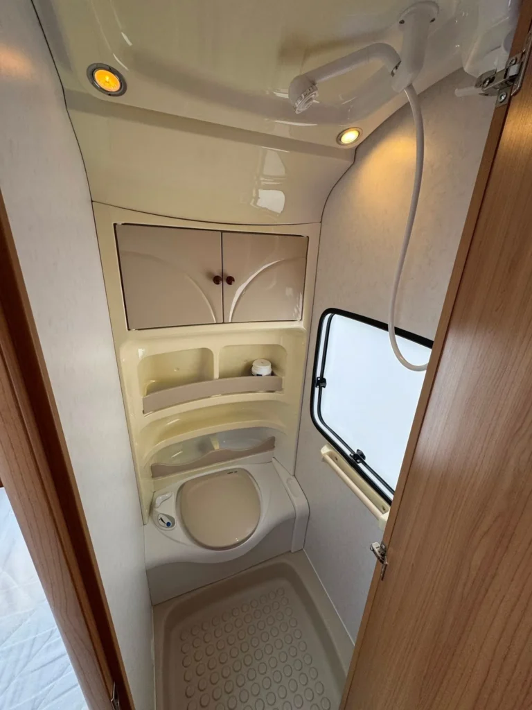 Koupelnový kout karavanu s toaletou a umyvadlem. Moderní a praktický design pro komfort na cestách.