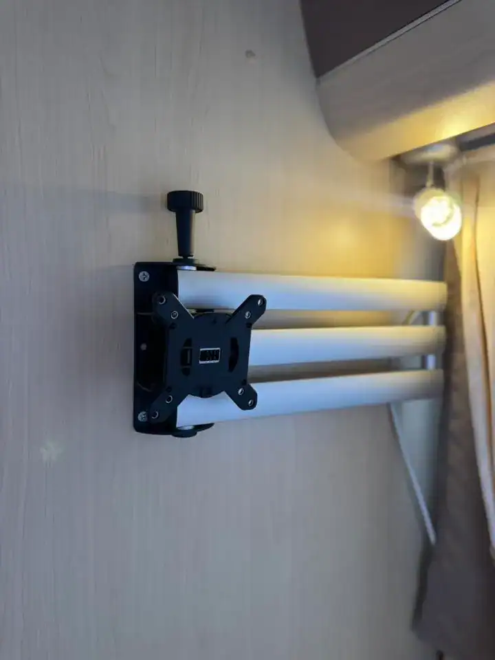 Na obrázku je montážní držák s teleskopickými rameny, pravděpodobně součást interiéru obytného přívěsu.