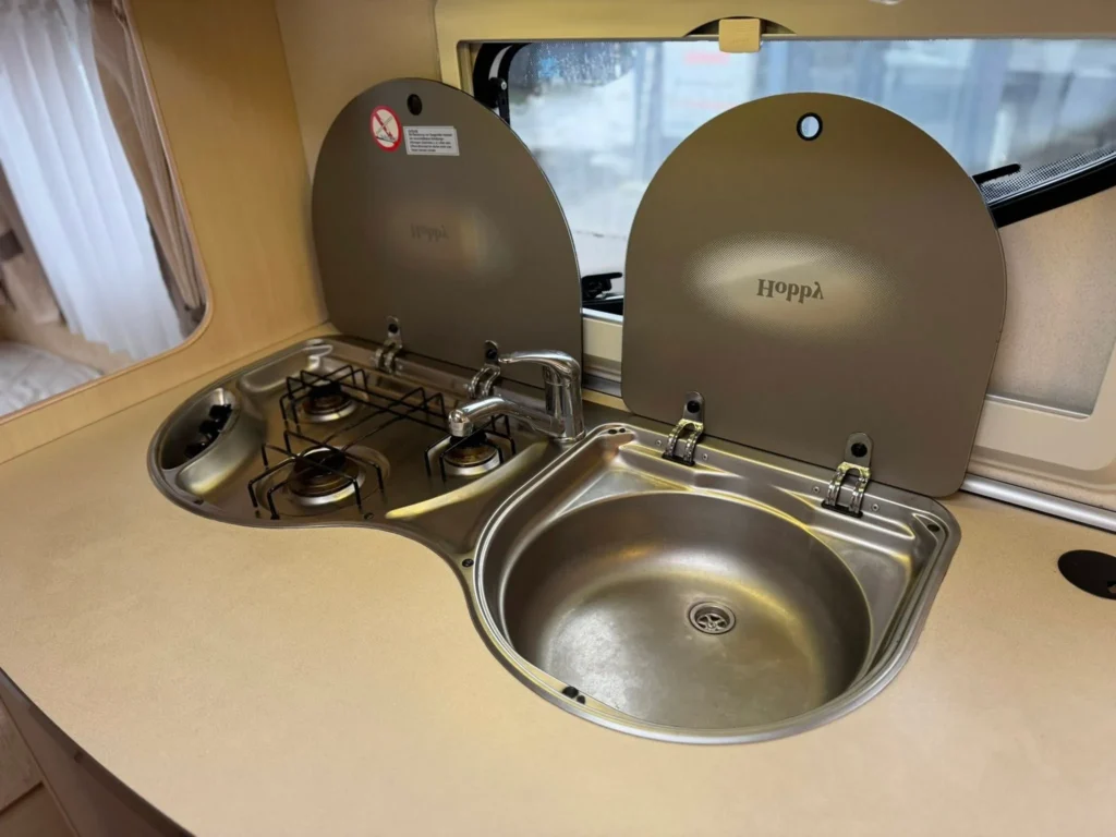 Obrázek ukazuje kuchyňský kout s dřezem a dvouplotýnkovým vařičem v karavanu značky Hoppa.