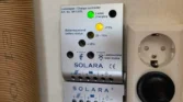 Na obrázku je nabíjecí regulátor SOLARA, ukazující stav baterie a provozní indikátor.