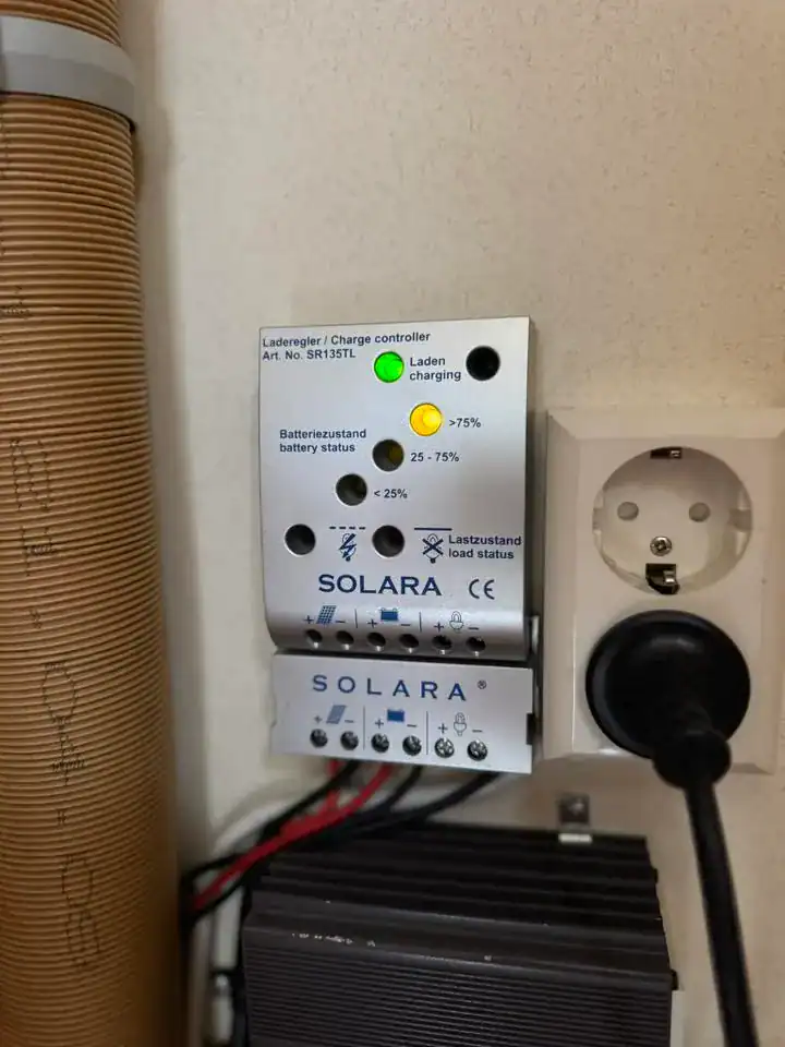 Na obrázku je nabíjecí regulátor SOLARA, ukazující stav baterie a provozní indikátor.