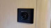 Na obrázku je termostat Truma Ultrafheat na stěně karavanu s dřevěným povrchem.