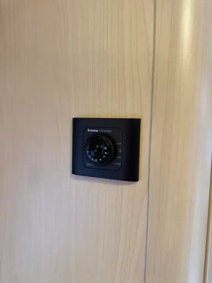 Na obrázku je termostat Truma Ultrafheat na stěně karavanu s dřevěným povrchem.