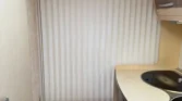 Interiér karavanu s kuchyňským koutem, skříněmi a žaluziemi. Moderní design v neutrálních barvách.