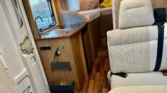Interiér obytného auta s kuchyňským koutem a pohodlným sezením. Ideální pro cestování a odpočinek.