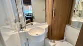 Koupelna obytného auta s moderním designem, umyvadlem a toaletou, ideální pro pohodlné cestování.