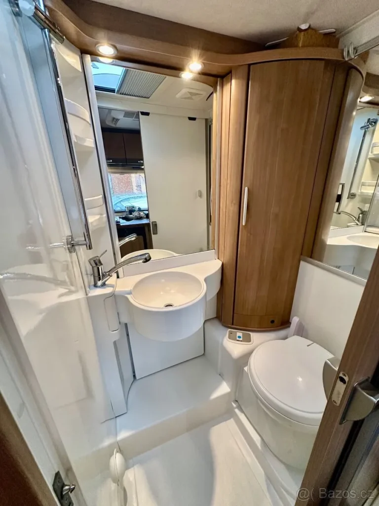 Koupelna obytného auta s moderním designem, umyvadlem a toaletou, ideální pro pohodlné cestování.