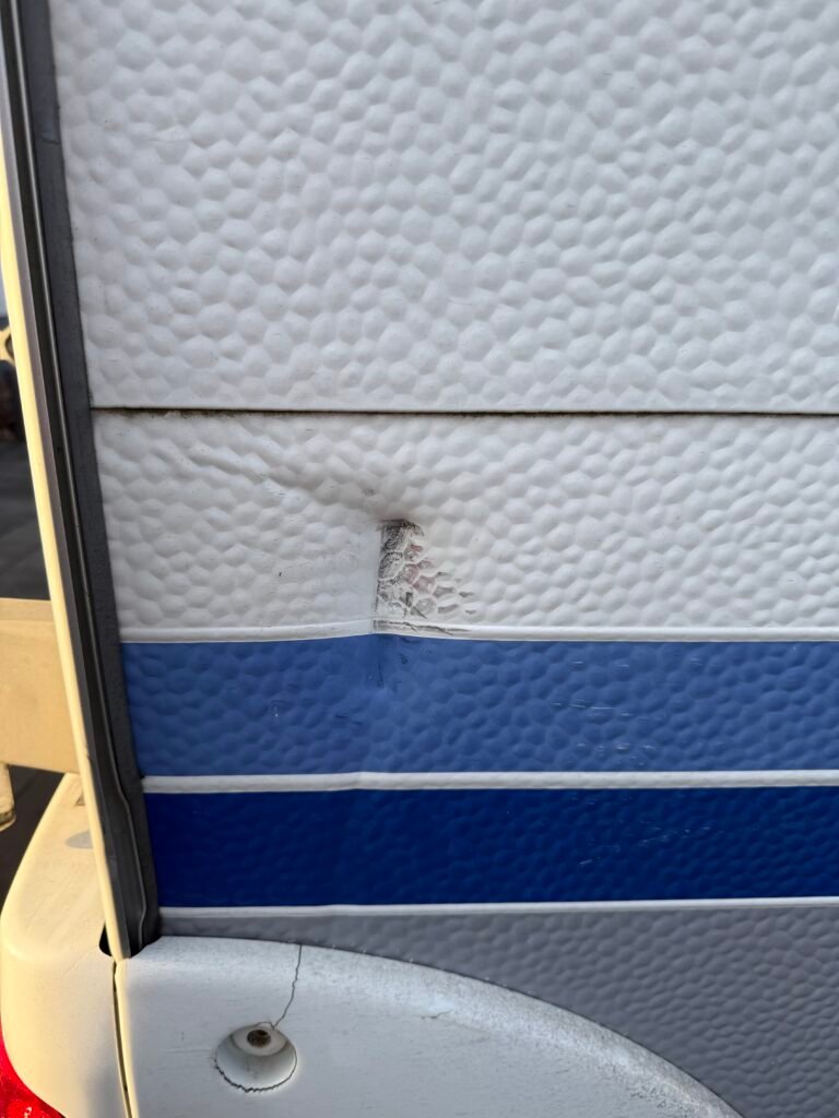 Na obrázku je poškození karavanu, detail zdi s promáčknutím a prasklinou.