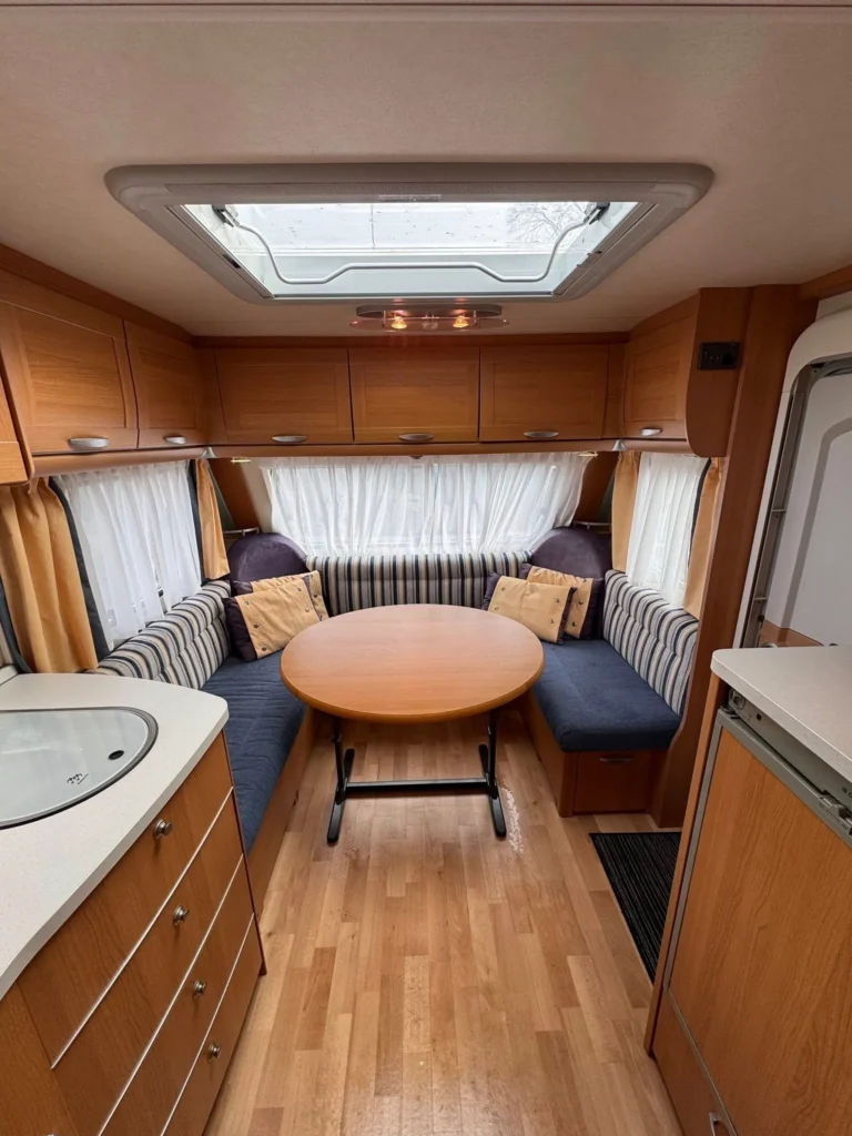 Interiér karavanu s dřevěnými prvky a prostorným sezením. Ideální pro pohodové cesty a odpočinek.