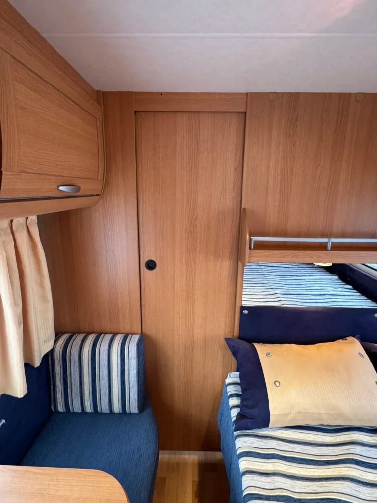 Obrázek interiéru karavanu s dřevěnými prvky a pohodlným posezením. Vhodný pro příjemné cestování.