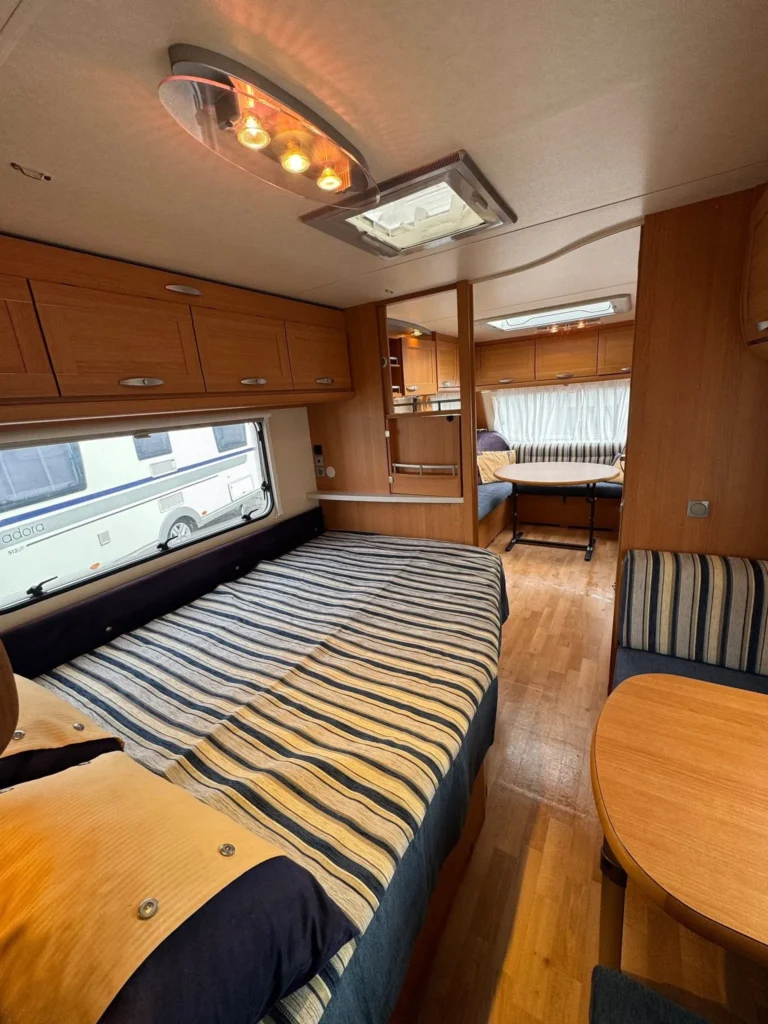 Obytné auto s prostorným interiérem, dřevěnými skříňkami a pohodlným posezením. Ideální pro dobrodružství!