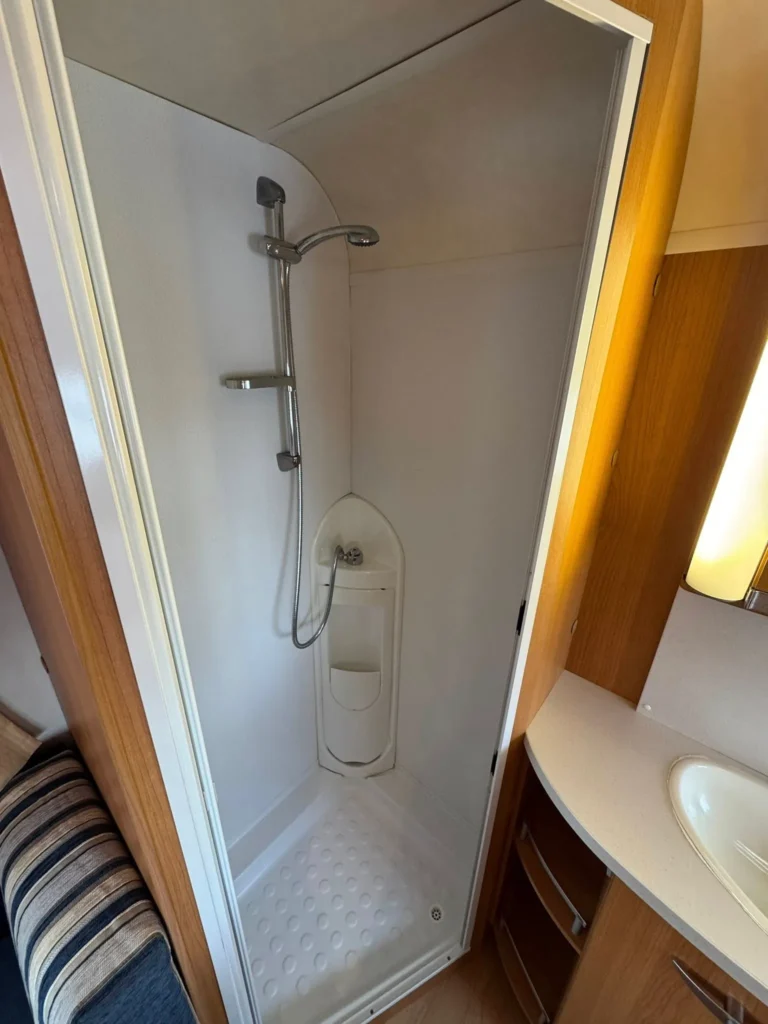Obrázek ukazuje sprchový kout v obytném autě. Koupelnový prostor je moderní a praktický.