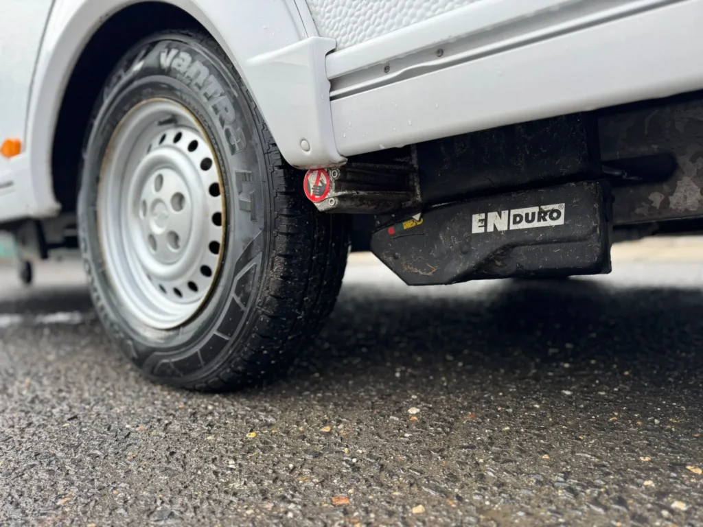 Obrázek ukazuje karavan s koly a pakny značky ENDURO. Ideální pro dobrodružství na cestách.