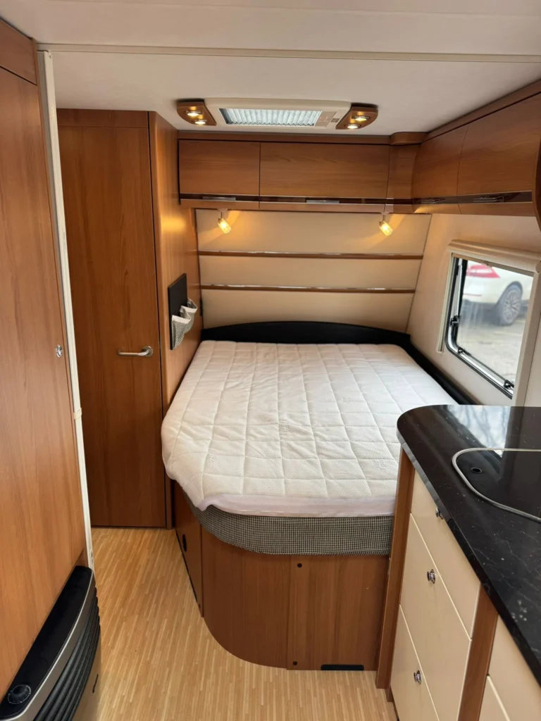 Obytné auto s útulným interiérem, ložnicí a moderní kuchyňkou. Ideální pro pohodlné cestování.