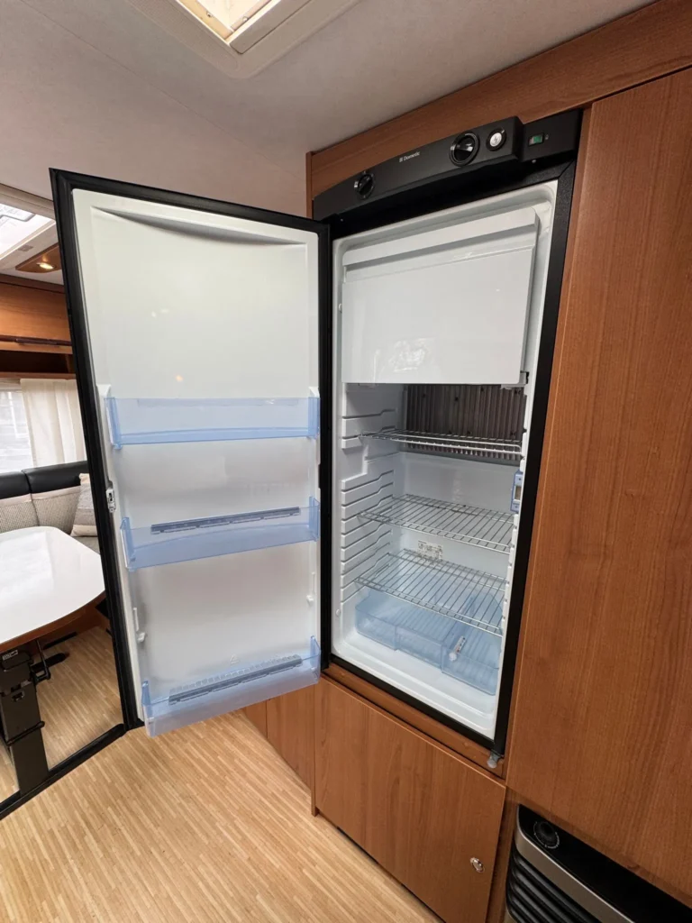 Obrázek interiéru karavanu s lednicí Dometic. Moderní a praktické uspořádání pro pohodlné cestování.