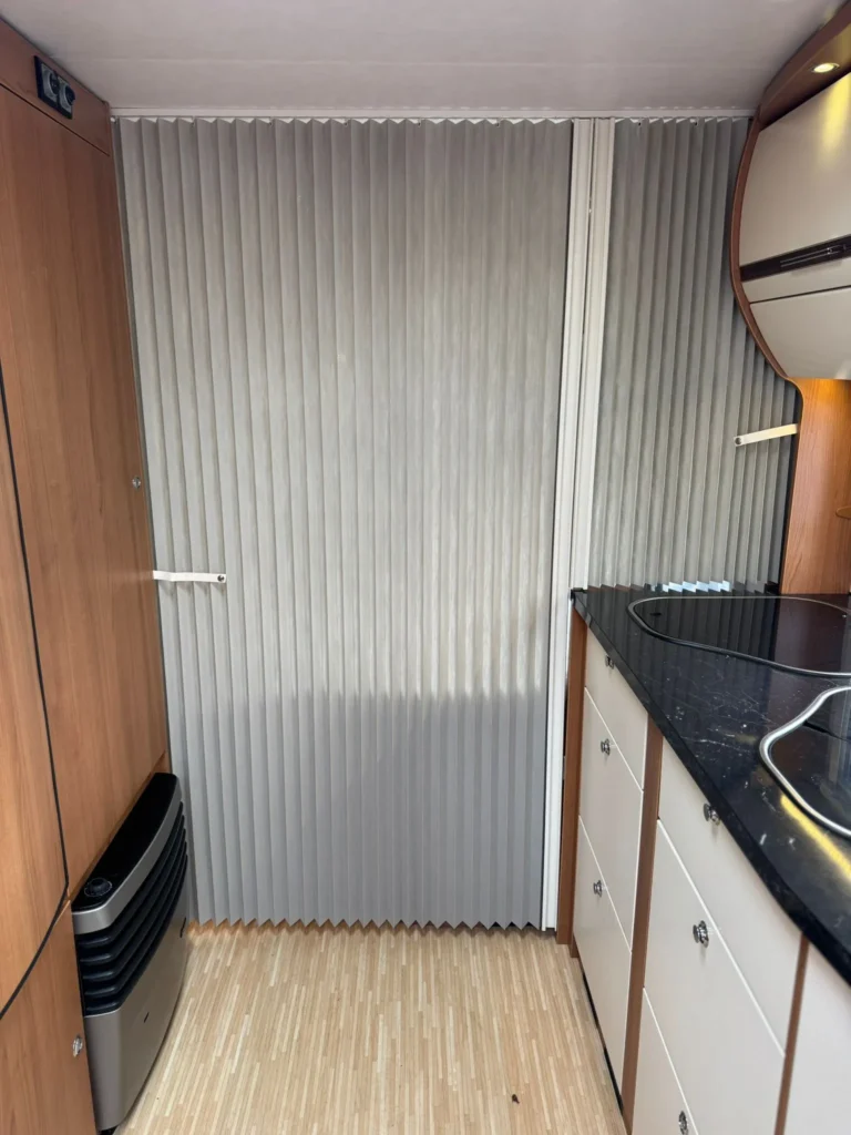 Obrázek interiéru obytného auta s moderními prvky a kuchyňským koutem. Vhodný pro pohodlné cestování.