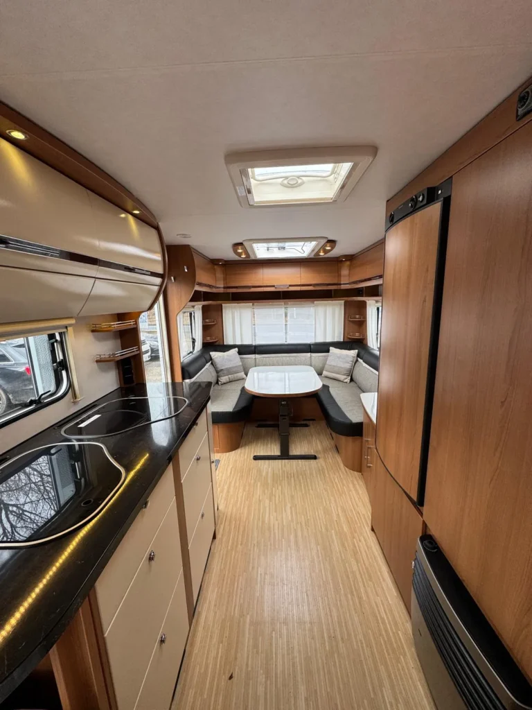 Interiér obytného auta s kuchyňskou linkou a pohodlným posezením. Ideální pro cestování a relaxaci.
