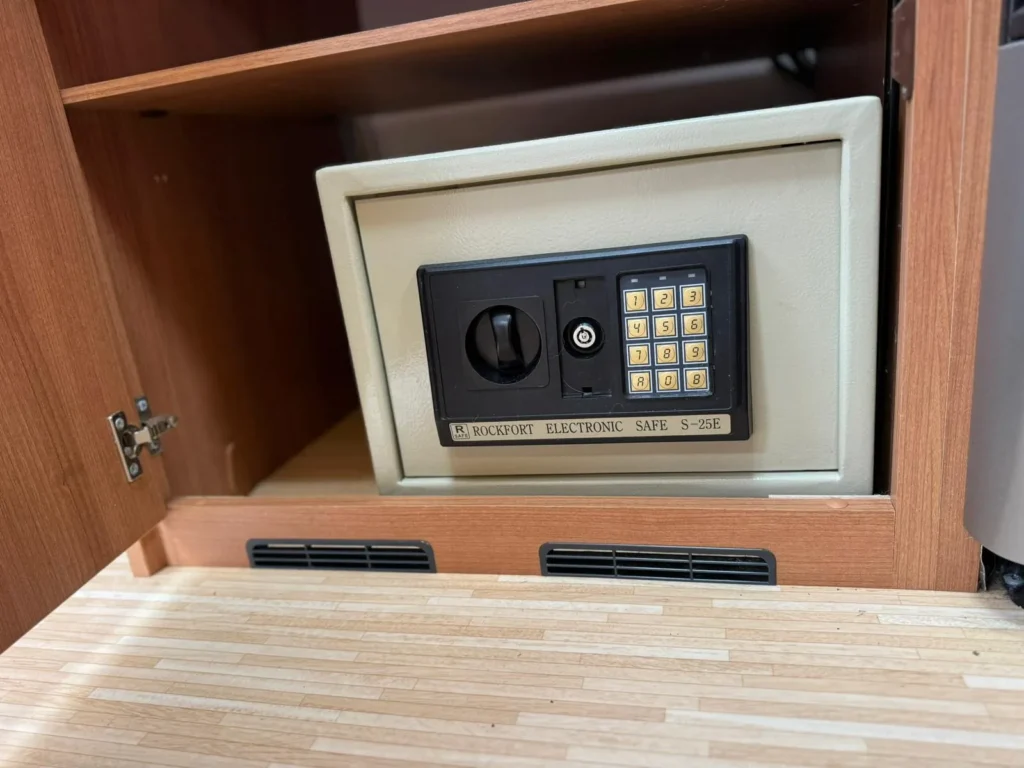 Obrázek ukazuje elektronický trezor v interiéru karavanu, ideální pro bezpečné uložení cenností.