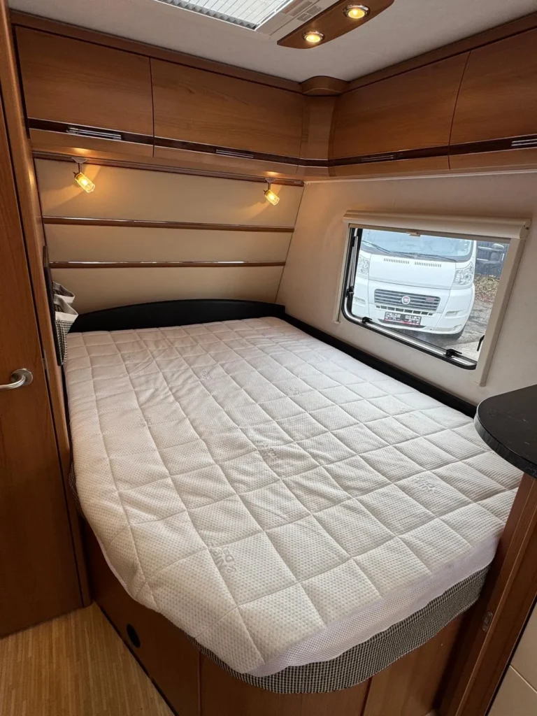 Na obrázku je karavan s pohodlnou postelí a moderním interiérem. Ideální pro vaše cestování!