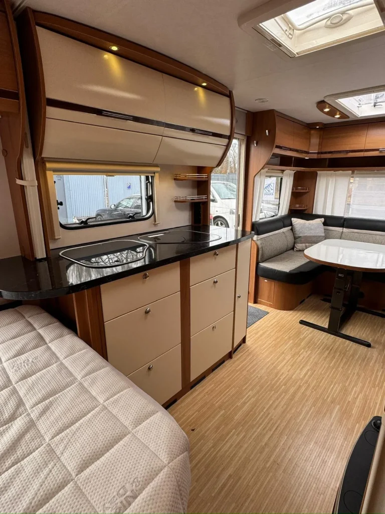 Interiér obytného vozu s moderním designem, kuchyňkou a pohodlným posezením. Ideální pro cestování a odpočinek.