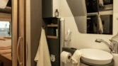 Obrázek zobrazuje elegantní koupelnu obytného auta, vybavenou umyvadlem a toaletou.