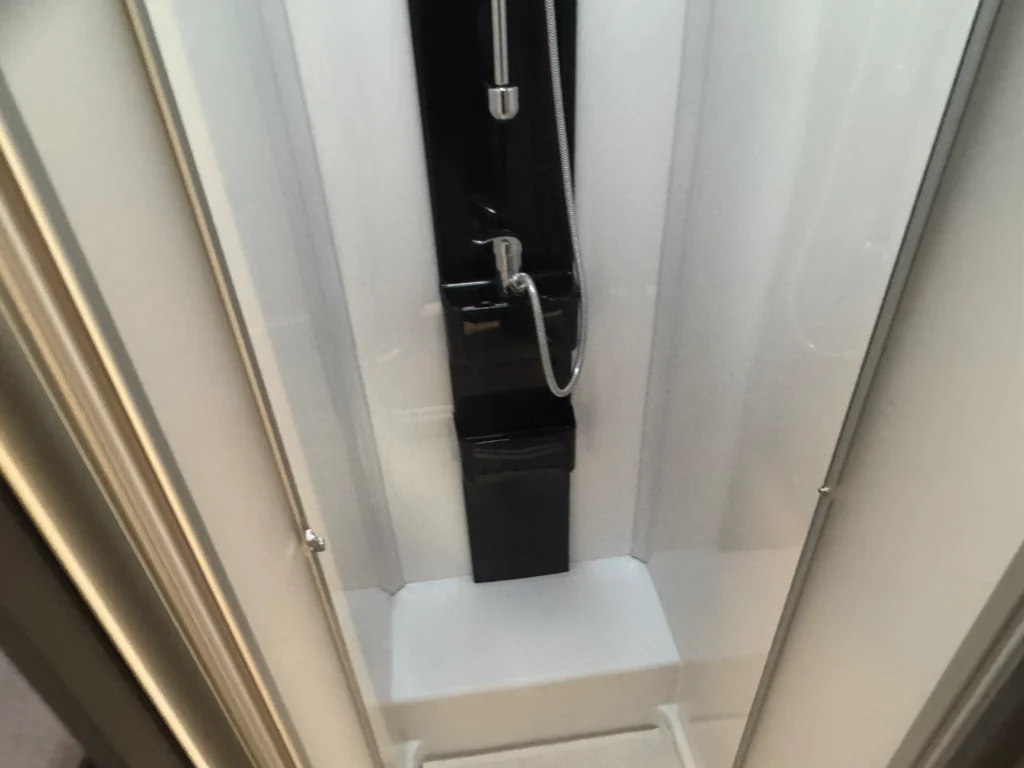 Obrázek ukazuje sprchový kout v obytném autě. Značka a model nejsou uvedeny.