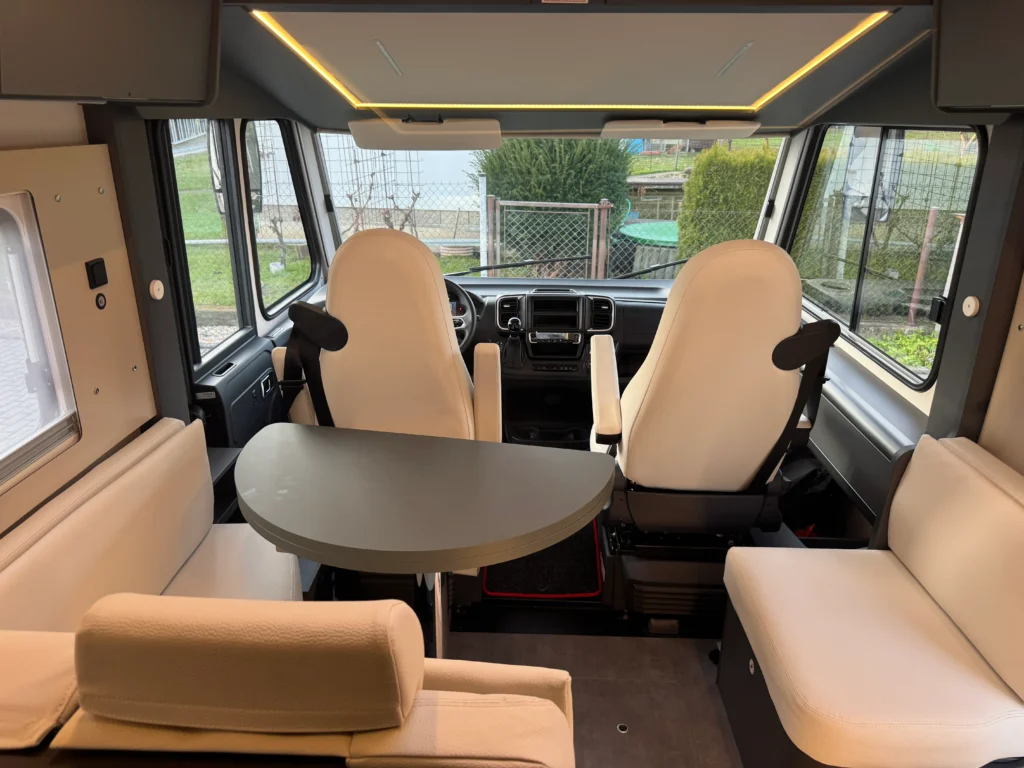 Obytné auto s moderním interiérem, pohodlná sedadla a stůl pro relaxaci. Ideální pro cestování a dobrodružství.