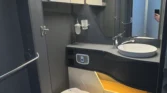 Luxusní interiér karavanu s moderním umyvadlem a toaletou. Ideální pro pohodlné cestování.