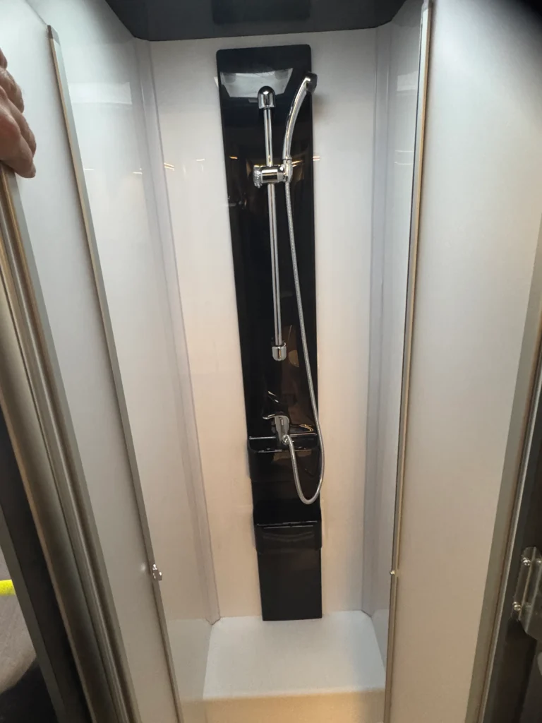 Obrázek ukazuje sprchový kout ve vozidle, detaily nejsou viditelné, nemohu určit značku nebo model.