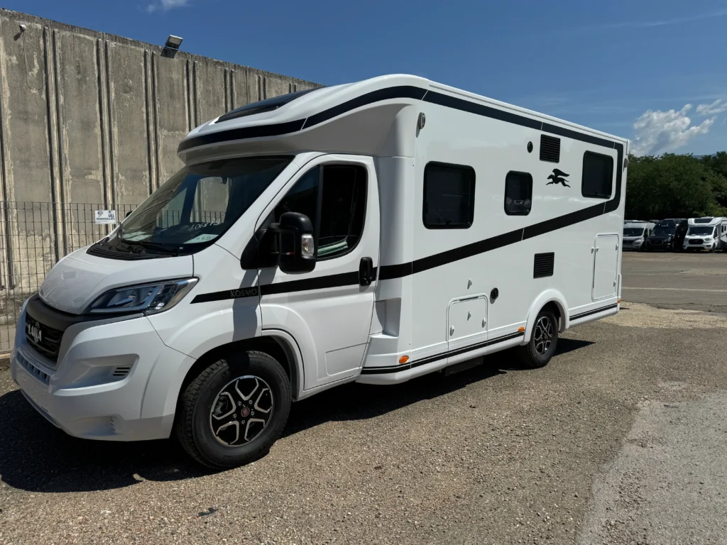 Bílý karavan značky KNAUS s moderním designem, viditelné okna a aerodynamická linie.