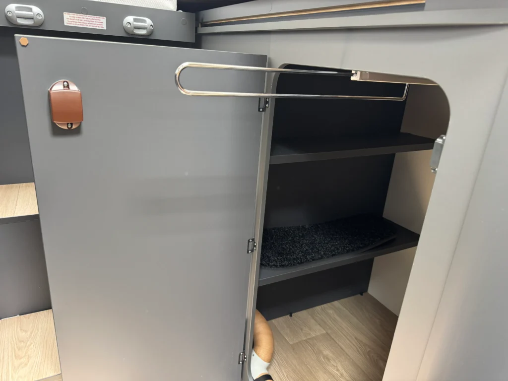 Obrázek interiéru z obytného auta. Stylový úložný prostor s policemi a dveřmi. Ideální pro praktičnost na cestách.