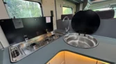 Kuchyňský kout s dřezem a vařičem v obytném voze, moderní design a funkčnost pro pohodlné vaření na cestách.