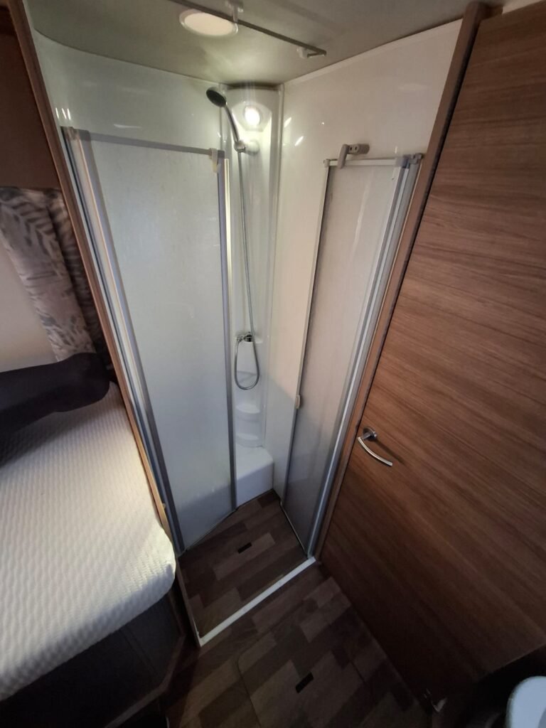 Obrázek interiéru obytného vozu s prostornou sprchou a komfortním zařízení. Ideální pro cestování!