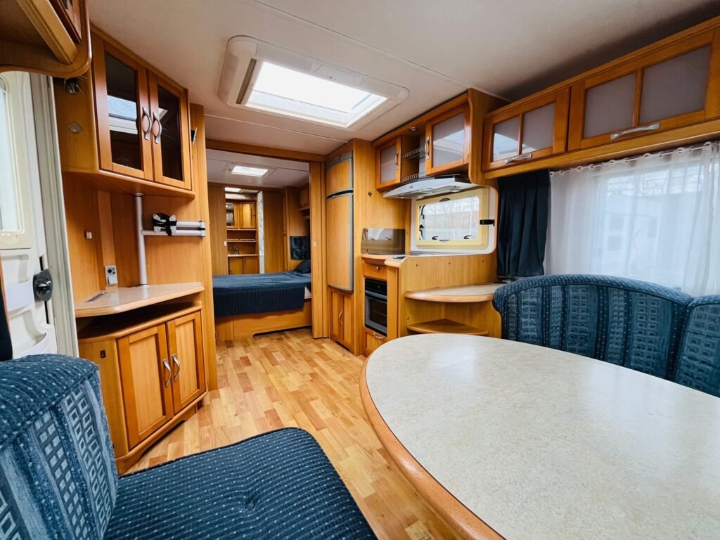 Interiér karavanu nabízí pohodlí s dřevěným nábytkem a moderním vybavením. Ideální pro cestování a odpočinek.