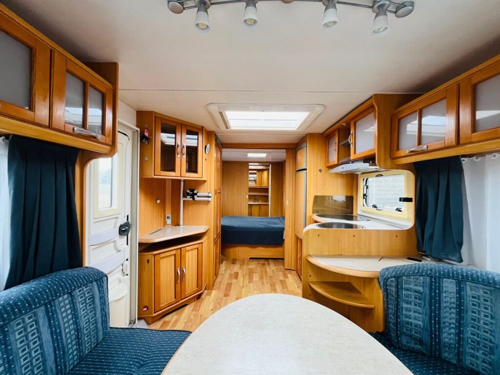 Interiér karavanu s dřevěným nábytkem a pohodlnými sedačkami, ideální pro kempování a cestování.