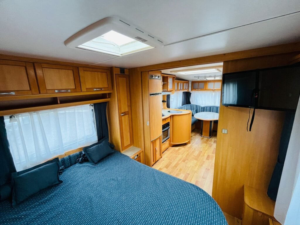 Interiér karavanu s pohodlným vybavením a dřevěnými akcenty. Ideální pro dobrodružství na cestách.