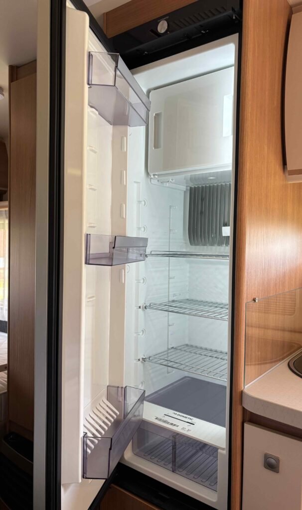 Obrázek ukazuje interiér obytného vozu s lednicí Dometic. Prostorné uspořádání pro pohodlí na cestách.