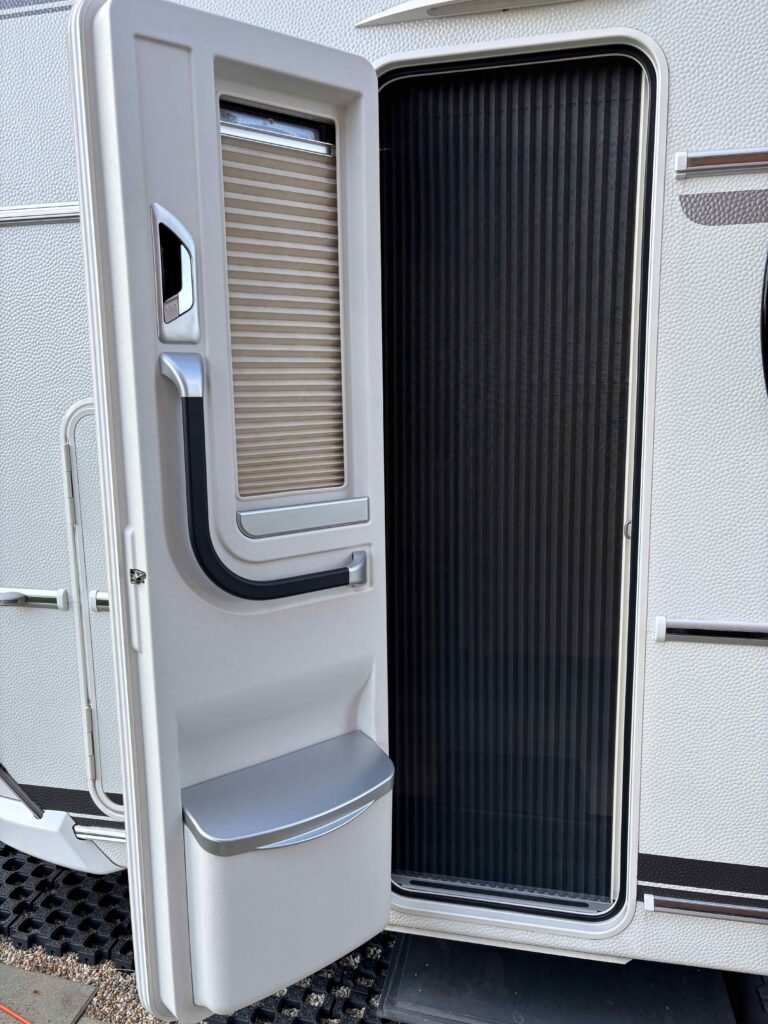 Na obrázku je dvojité dveře karavanu s roletou a úložným prostorem. Značku ani model není možné určit.
