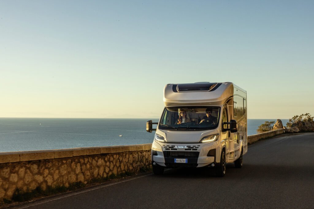 Obytné auto Laika projíždí po silnici s výhledem na moře. Ideální pro vaše dobrodružství!