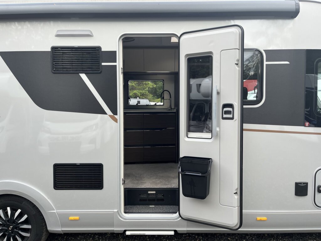 Obytné auto s otevřenými dveřmi, moderní design a prostorný interiér. Značka a model nejsou viditelné.