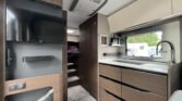 Interiér moderního obytného auta s kuchyňským koutem a pohodlnými úložnými prostory. Ideální pro cestování.