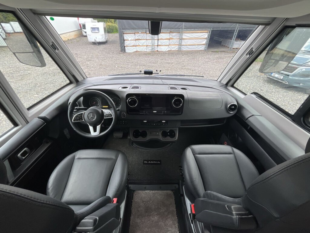 Interiér obytného auta Mercedes s pohodlnými sedadly a moderními technologiemi pro cestování.