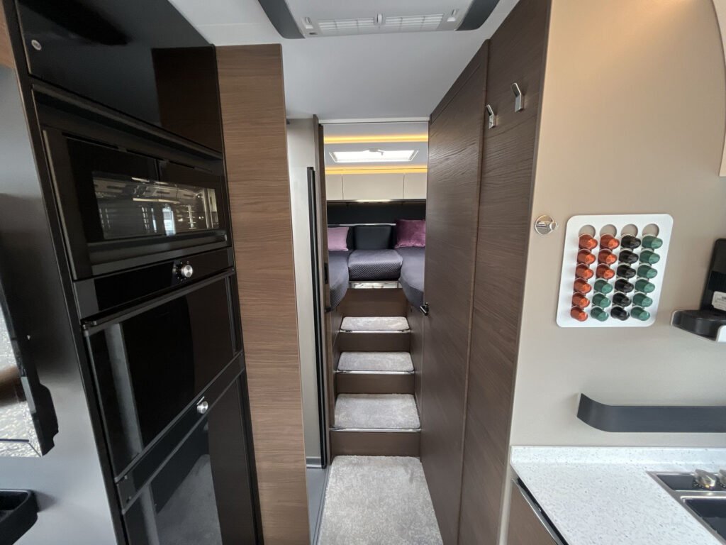 Interiér moderního karavanu, dobře vybavený kuchyní a pohodlným prostorem na spaní. Ideální pro dobrodružství.