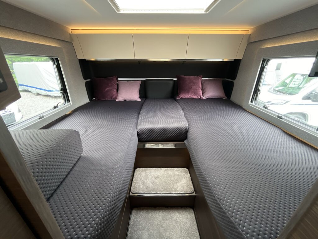 Interiér obytného vozu s pohodlnými lůžky, příjemnými polštáři a moderním designem. Skvělé pro relaxaci na cestách.