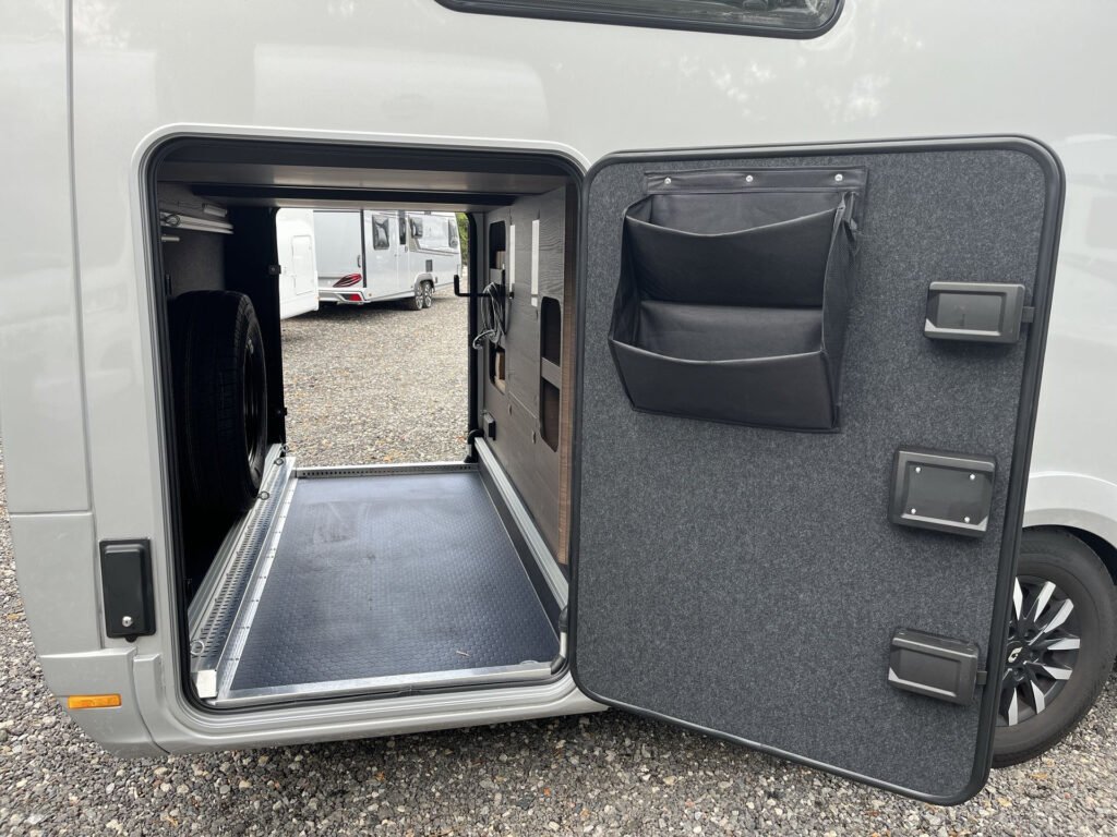 Obrázek zobrazuje úložný prostor obytného auta s tmavou podlahou a zástěrou. Značka a model nejsou viditelné.