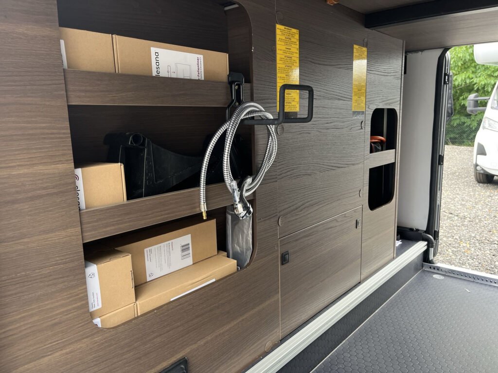 Obrázek interiéru obytného auta s úložným prostorem. Značka a model nejsou uvedeny.