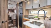 Obrázek interiéru obytného auta s moderní kuchyní a komfortním prostorem na spaní.
