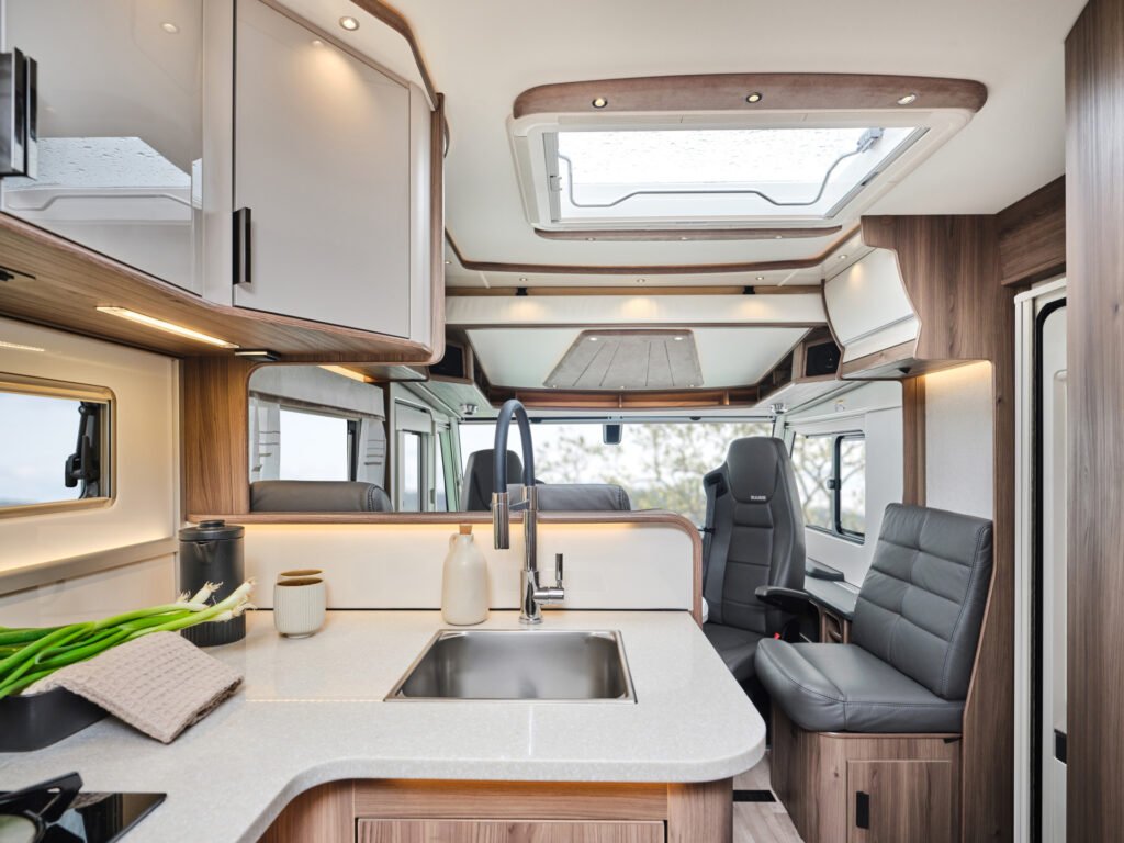 Interiér obytného auta s moderním designem a plně vybavenou kuchyní. Ideální pro dobrodružství na cestách.