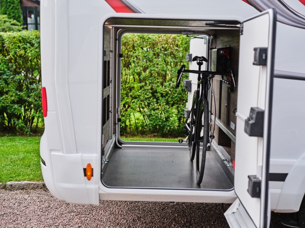 Obrázek zobrazuje obytné auto s úložným prostorem pro kolo. Značka a model nejsou uvedeny.